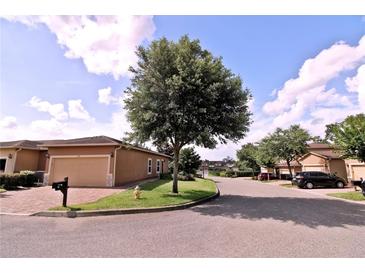 Beige home with a large garage, brick driveway, well maintained lawn, and mature trees at 201 Walter Stevens Way, Deland, FL 32724