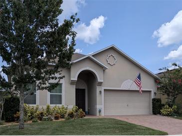 Charming single-story home with a well-manicured lawn and a welcoming two-car garage and American flag at 223 W Fiesta Key Loop, Deland, FL 32720