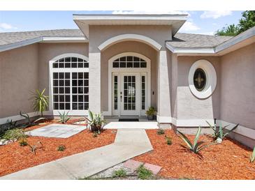 Stunning front entrance with an arched doorway, double doors and beautiful landscaping at 570 Cypress Ave, Orange City, FL 32763