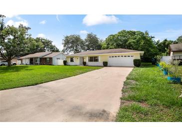 Charming single-story home with yellow paint, attached garage, and a long driveway at 952 N Fairbairn Dr, Deltona, FL 32725