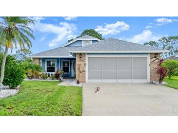 Charming single-story home with well-maintained landscaping, a blue and brick facade, and an attached two-car garage at 123 Wood Ibis Ct, Daytona Beach, FL 32119