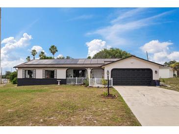 Charming single-story home featuring solar panels, a dark roof, and a well-kept front lawn under a blue sky at 1660 E Apache Cir, Deltona, FL 32725