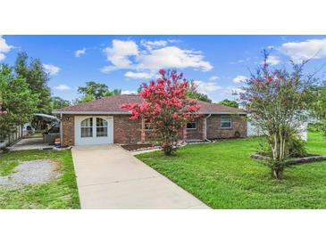 Charming brick home featuring a well-maintained lawn and blooming pink flowers in the front yard at 1702 Palmetto Ave, Deland, FL 32724