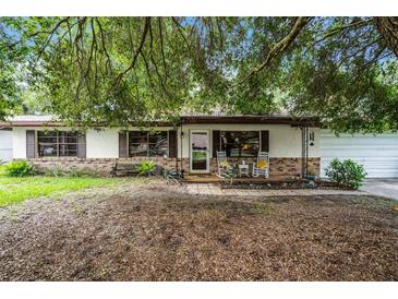 Charming single-story home featuring a brick facade and cozy front porch with rocking chairs and bench at 270 Sandyhook Ln, Deland, FL 32724
