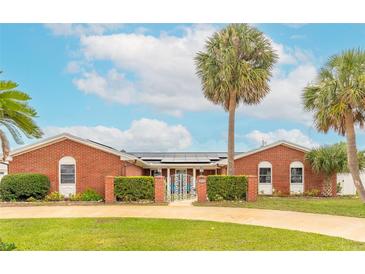Charming brick home features lush landscaping, solar panels, and a gated entrance at 2724 N Halifax Ave, Daytona Beach, FL 32118