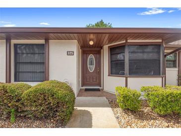 Inviting condo front door with decorative glass, manicured bushes, and brick accents on the walkway at 325 Homewood Ave # 10I, Debary, FL 32713