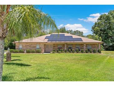 Charming brick home featuring a well-manicured lawn, complemented with solar panels for energy efficiency at 519 Donaldson Dr, Debary, FL 32713