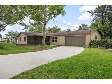 Charming single-story home with well-maintained lawn, a large tree, and a driveway leading to an attached garage at 5402 Turton Ln, Port Orange, FL 32127