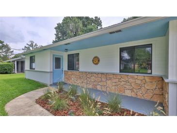 Charming front porch with stone accent wall, blue door, and landscaped garden bed at 1017 Chippewa Trl, Daytona Beach, FL 32117