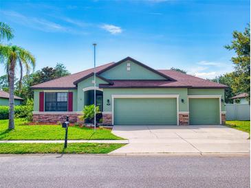 Inviting one-story home features a well-manicured lawn, three-car garage, and beautiful desert-toned color palette at 112 Tuscany Bend St, Daytona Beach, FL 32117