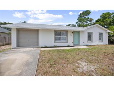 Charming single-story home with a gray garage door, white exterior, and bright blue front door at 2831 Fifer Dr, Deltona, FL 32738