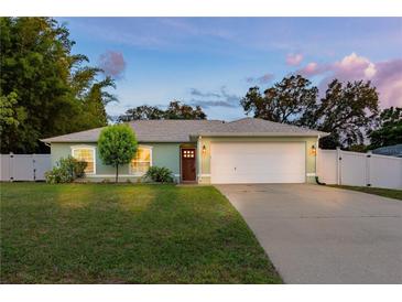 Charming one-story home featuring a well-manicured lawn, mature trees, and a spacious two-car garage at 3013 Hunkin Cir, Deltona, FL 32738