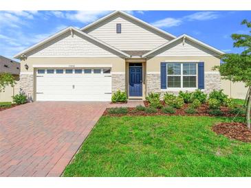 Charming single-story home featuring a well-manicured lawn, brick driveway, and blue shutters at 33436 Shutterfly Way, Sorrento, FL 32776
