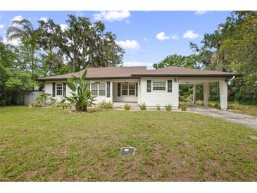 Charming single-story home with white siding, dark shutters, carport, and well-maintained front lawn at 431 S Stone St, Deland, FL 32720