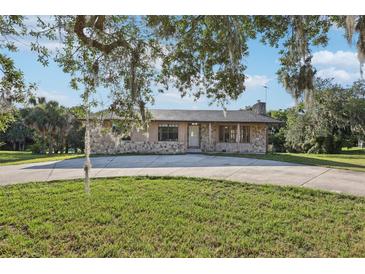 Charming stone facade home with a well-manicured lawn and mature trees creating curb appeal at 5759 Dogwood Rd, Port Orange, FL 32127