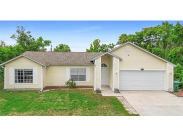 Charming single-story home featuring an attached garage, well-maintained lawn, and light yellow siding at 685 N Firwood Dr, Deltona, FL 32725