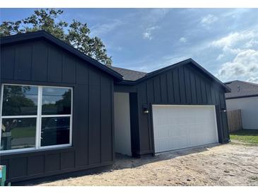 Modern dark gray home with a white garage door and trimmed window at 822 W 24Th St, Sanford, FL 32771