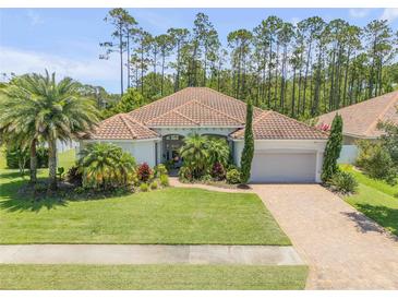 Charming single-story home with a well-manicured lawn, lush landscaping, and a tile roof at 101 Briargate Look, Ormond Beach, FL 32174