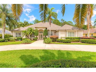 Charming home with a circular driveway, lush landscaping, and mature palm trees at 15 Cambridge Trce, Ormond Beach, FL 32174