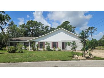 Charming single-story home with white brick facade, landscaped front yard, and lush greenery at 1730 Birmingham Ave, Daytona Beach, FL 32117