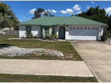 Charming single-story home with a well-manicured lawn, attractive landscaping, and a green metal roof at 1973 S Old Mill Dr, Deltona, FL 32725