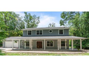 Charming two-story home featuring a large, covered front porch with white pillars and a well-maintained lawn and garage at 2 E Kelly Park Rd, Apopka, FL 32712