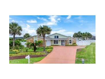 Inviting single-story home featuring a lush lawn, palm trees, and a long driveway at 3 Sea Dance Ter, Ormond Beach, FL 32176