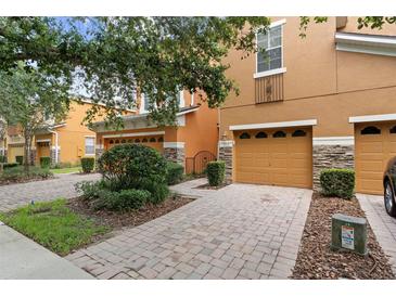 Charming two-story townhome with a well-maintained front yard, featuring a brick-paved driveway and manicured landscaping at 5060 Cypress Branch Pt, Oviedo, FL 32765