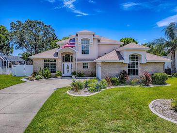 Charming two-story home boasts a manicured lawn, mature landscaping, and an inviting entrance with brick accents at 5936 Boggs Ford Rd, Port Orange, FL 32127