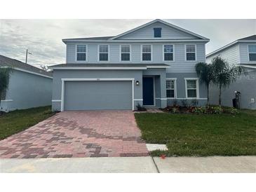 Two-story house with gray siding, brick driveway, and landscaping at 260 Crossings Ave, St Cloud, FL 34771