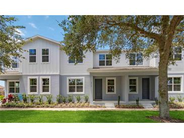 Two-story townhome with gray and white exterior, landscaping, and front porch at 6915 Five Oaks Dr, St Cloud, FL 34773