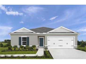 One-story home with gray siding, white garage door, and landscaping at 306 Biltmore Blvd, Dundee, FL 33838
