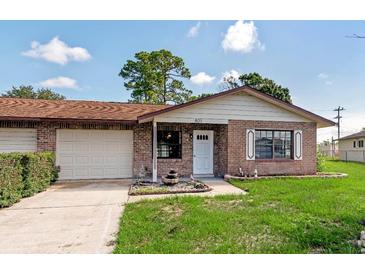 Brick ranch home with attached garage, landscaping, and a fountain at 801 Egret Ct, Edgewater, FL 32141