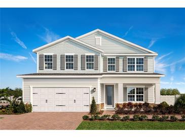 Two-story house with a white and gray exterior, a three-car garage, and a well-manicured lawn at 366 Hammock Oaks Blvd, Lady Lake, FL 32159