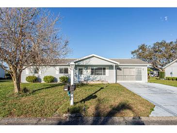 Charming single-story home with a well-manicured lawn, screened-in garage, and beautiful landscaping at 17975 Se 106Th Ct, Summerfield, FL 34491