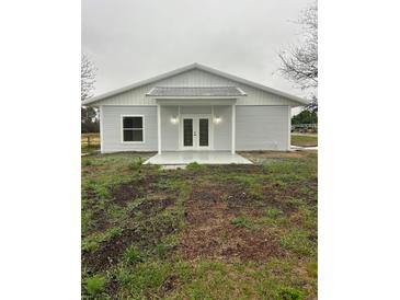 Charming single-story home featuring a metal roof, double doors, and light gray siding at 36702 Calhoun Rd, Eustis, FL 32736