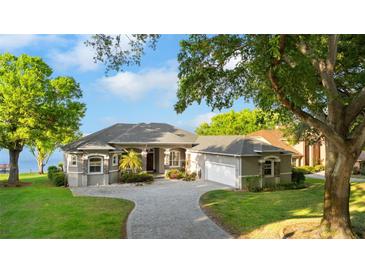 Spacious home with a gray exterior, a well-manicured lawn, mature trees, and a winding brick driveway at 248 Lake Tennessee Dr, Auburndale, FL 33823