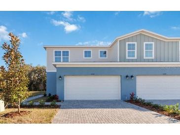 Charming townhome features an attached two car garage, blue paint, and lovely architecture under a beautiful blue sky at 5248 Luisa Ct, St Cloud, FL 34771