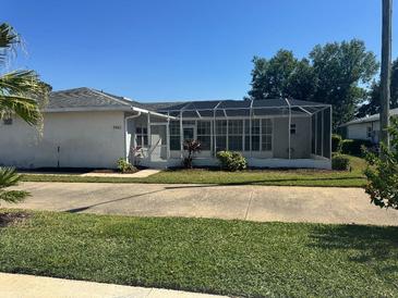 Charming home featuring a screened-in porch, well-maintained lawn, and lush landscaping at 2963 Poplar Ave, Leesburg, FL 34748