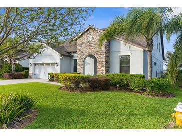 Charming home with a well-manicured lawn, stone accents, and mature landscaping creates a welcoming curb appeal at 1382 Heritage Landings Dr, Lakeland, FL 33805