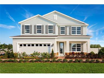 Charming two-story home showcasing a blend of stone and siding, complemented by a manicured lawn and colorful flower beds at 1327 Whispering Ln, Minneola, FL 34715