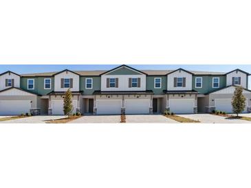 View of the exterior of the townhomes featuring a garage, lawn, and neutral color palette at 1096 Desert Candle Dr, Ocoee, FL 34761