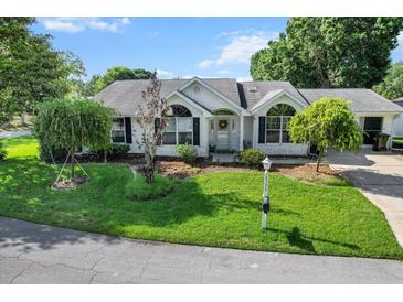 Charming white brick home featuring lush landscaping and an inviting front lawn at 8596 Sw 108Th Place Rd, Ocala, FL 34481