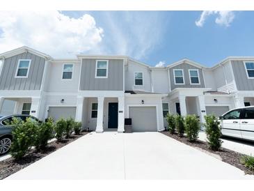 Charming townhome with white and gray exterior, attached garage, and well-maintained landscaping at 7433 Stone Creek Trl, Kissimmee, FL 34747