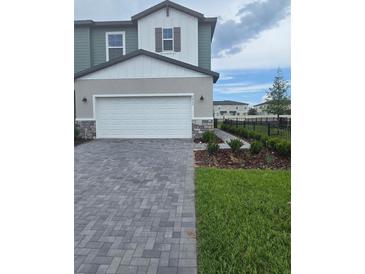 Two-story home featuring a two-car garage, stone accents, manicured lawn, and a paved driveway at 2453 Magnolia Reserve Rd, Ocoee, FL 34761