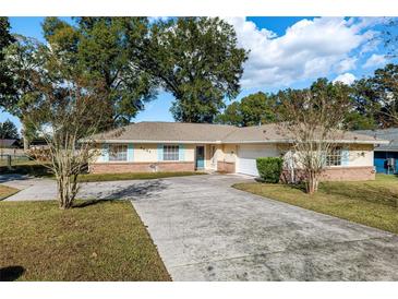 Charming one-story home with a well-maintained lawn, a long driveway, and a two-car garage at 4851 Ne 7Th St, Ocala, FL 34470