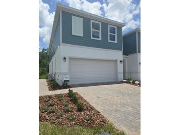 New two-story home featuring a two-car garage, manicured lawn, and a welcoming facade with blue horizontal siding at 1125 Red Buckeye Ct, Deland, FL 32720