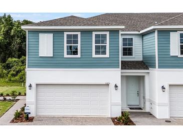Charming two-story home with a white garage door and light blue siding and white trim at 1145 Red Buckeye Ct, Deland, FL 32720