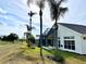Home with a screened lanai backing onto an expansive green lawn and highlighted by tall palm trees against a sunny, blue sky at 255 Royal Palm Dr, Davenport, FL 33837