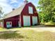 Grand red barn featuring white trim and spacious garage doors in a serene countryside setting at 850 Eden Dr, Saint Cloud, FL 34771